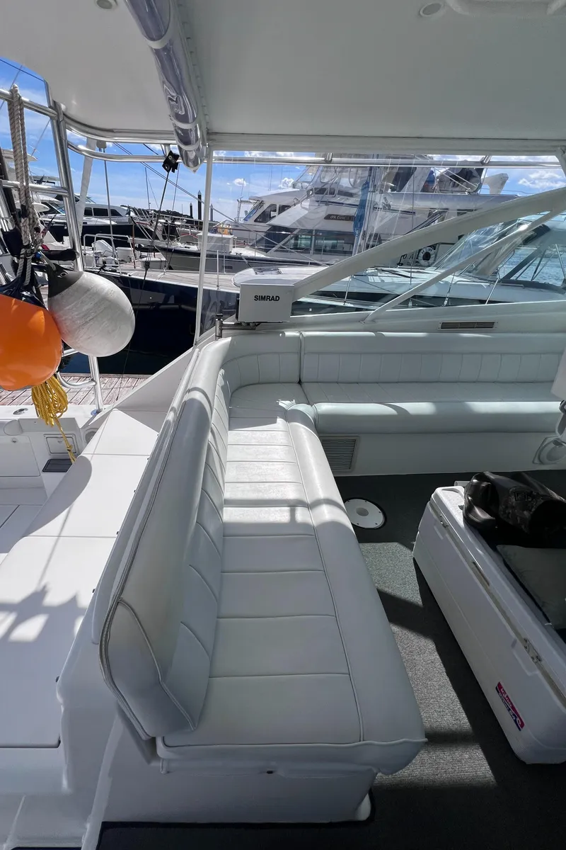 Slide: The Image of 2001 Cabo 45 Express yacht interior with white seating and marina view. - 6