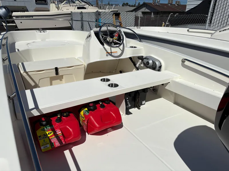 Slide: The Image of 2025 Boston Whaler 160 Super Sport interior with steering wheel, seating, and fuel containers. - 4