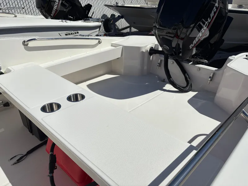 Slide: The Image of 2025 Boston Whaler 160 Super Sport boat interior with Mercury engine and cup holders. - 7