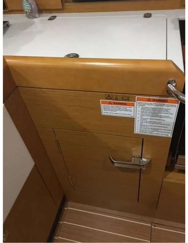 Slide: The Image of 2017 Jeanneau Sun Odyssey 44 DS interior, featuring a wooden cabinet with safety instructions. - 17