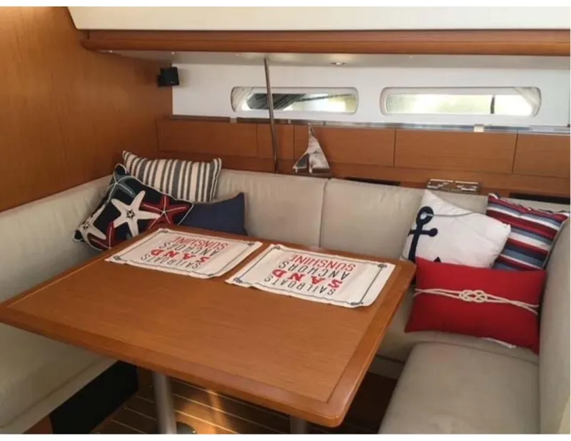 Slide: The Image of Interior of 2017 Jeanneau Sun Odyssey 44 DS with nautical-themed cushions and wooden table. - 8