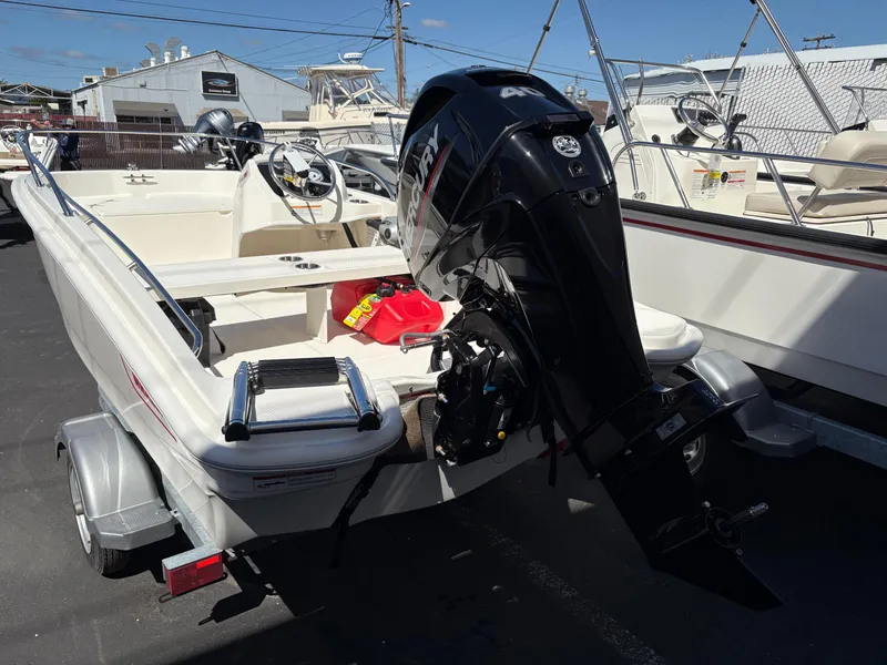 Slide: The Image of 2025 Boston Whaler 130 Super Sport boat with outboard motor on trailer. - 2