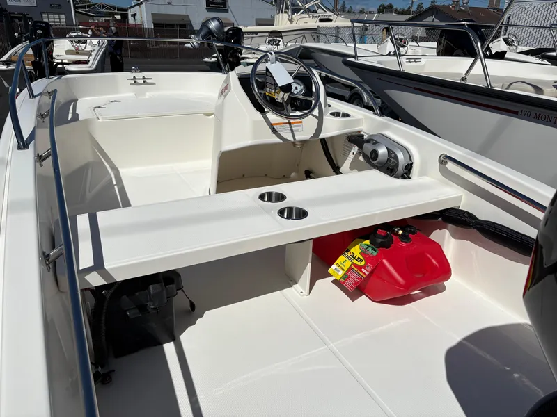 Slide: The Image of 2025 Boston Whaler 130 Super Sport boat interior with steering wheel and seating area. - 3