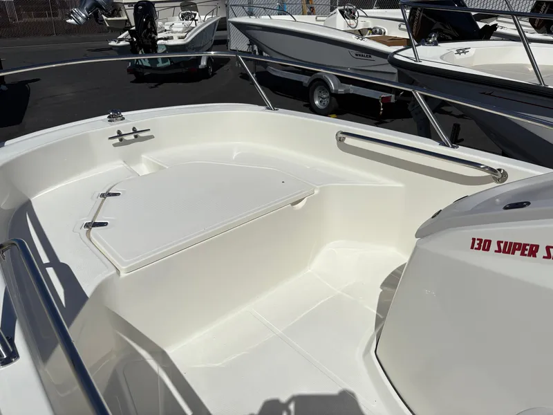 Slide: The Image of 2025 Boston Whaler 130 Super Sport boat interior, featuring sleek white seating and storage. - 4