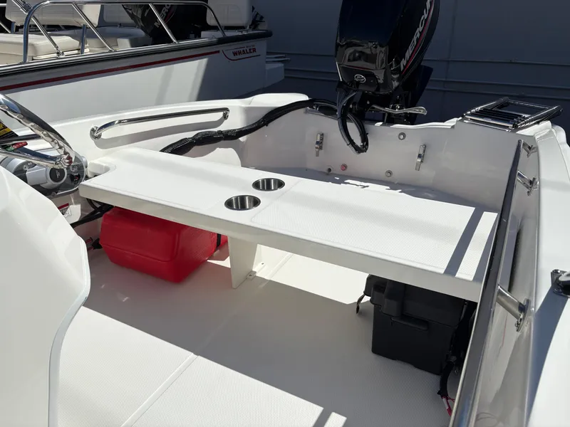 Slide: The Image of 2025 Boston Whaler 130 Super Sport boat interior with seating and engine view. - 5