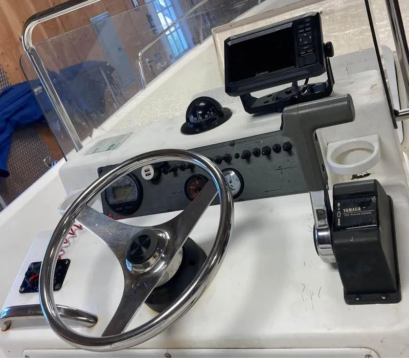 Slide: The Image of 2003 Aquasport 200 Osprey boat dashboard with steering wheel and controls. - 2