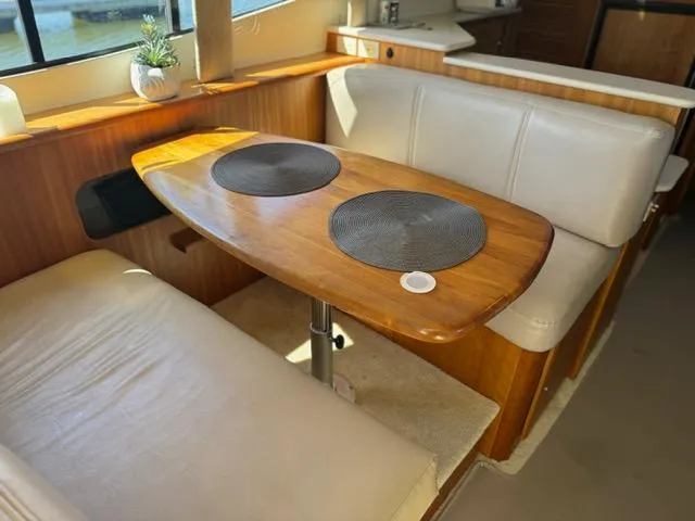 Slide: The Image of Interior of 2002 Silverton 330 Sport Bridge with wooden table and seating area. - 10
