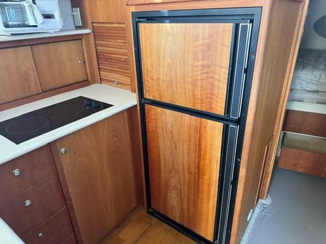 Slide: The Image of 2002 Silverton 330 Sport Bridge kitchen with wood cabinetry and compact fridge. - 13