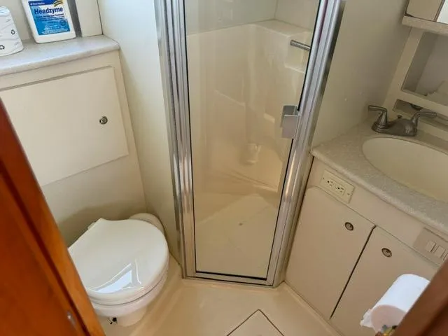 Slide: The Image of Bathroom interior of 2002 Silverton 330 Sport Bridge with shower, toilet, and sink. - 16