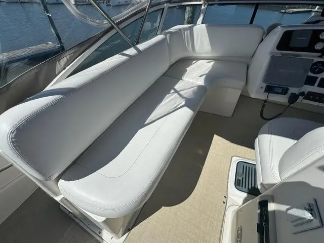 Slide: The Image of 2002 Silverton 330 Sport Bridge interior with white seating and helm, docked at marina. - 5
