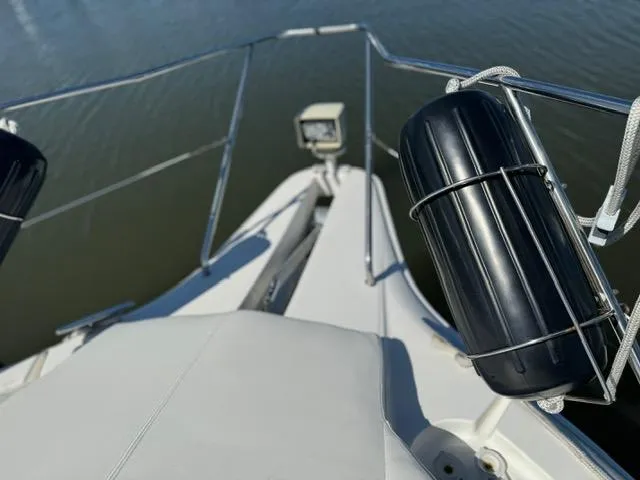 Slide: The Image of 2002 Silverton 330 Sport Bridge boat deck with railing and fender on calm water. - 9