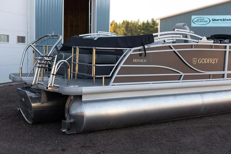 Slide: The Image of 2025 Godfrey Monaco 235 SFL pontoon boat on trailer, displayed indoors for sale. - 2