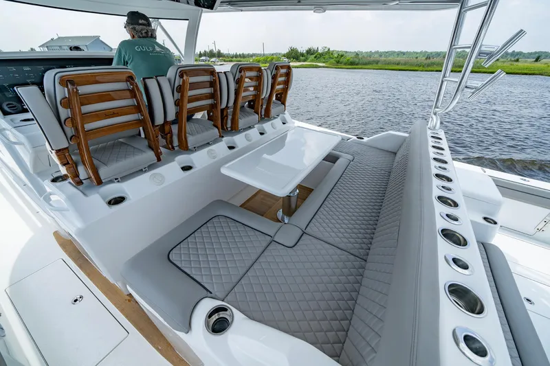 Slide: The Image of 2024 Valhalla V-55 Center Console boat interior with seating and table, on a calm waterway. - 13