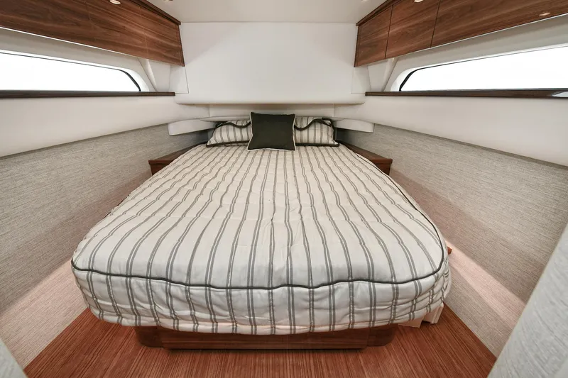 Slide: The Image of 2024 Valhalla V-55 Center Console cabin with striped bedding and wood accents. - 38