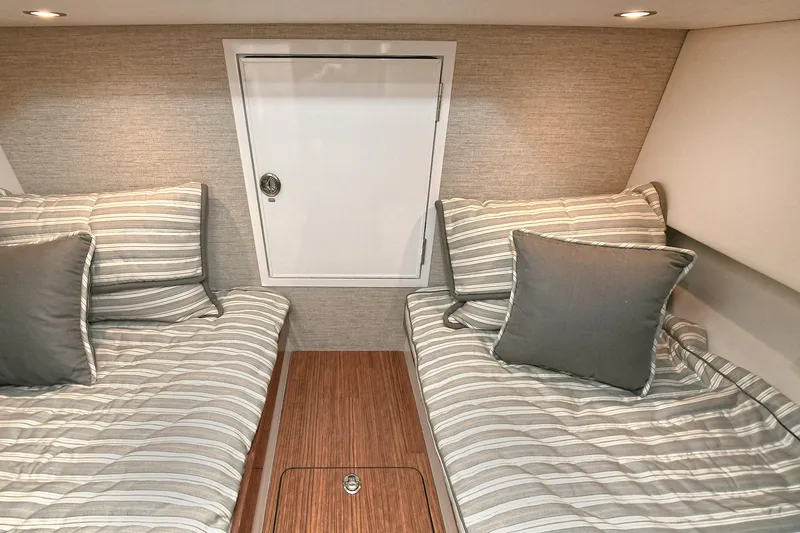 Slide: The Image of 2024 Valhalla V-55 Center Console cabin with twin beds and striped bedding. - 40