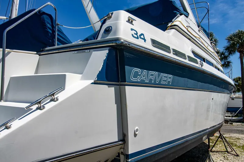 Slide: The Image of 1989 Carver 340 Santego boat, white and blue exterior, docked under clear sky. - 6