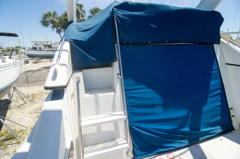 Slide: The Image of 1989 Carver 340 Santego boat with blue canvas cover and steps, docked outdoors. - 15