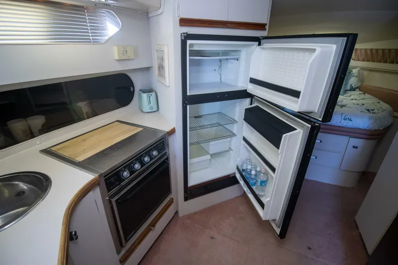 Slide: The Image of 1989 Carver 340 Santego yacht kitchen with open fridge, stove, and sink. - 20