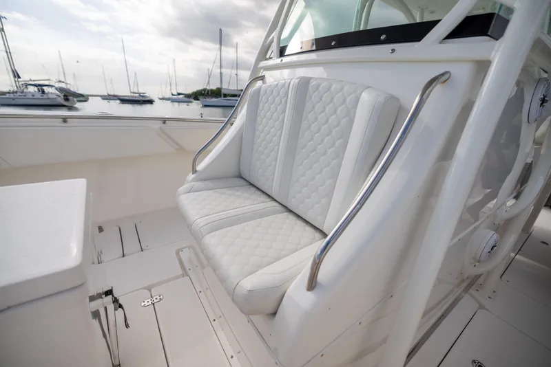 Slide: The Image of 2007 Fountain 34 Center Console boat with white cushioned seating, docked near sailboats. - 8