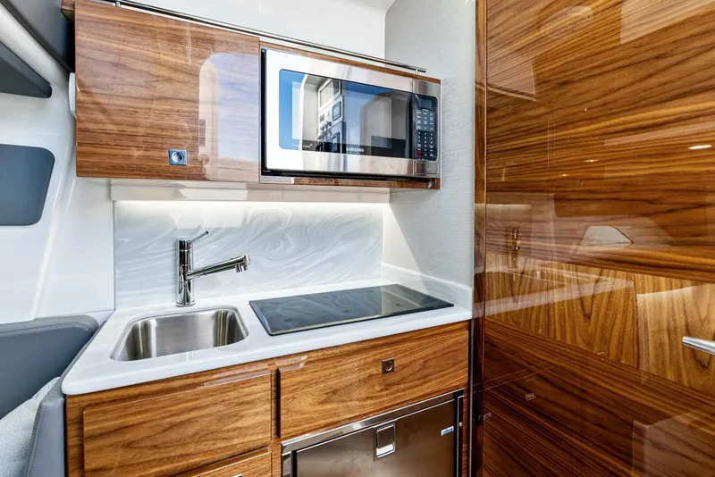 Slide: The Image of 2025 Valhalla Boatworks V-46 interior kitchen with wood cabinetry, sink, and microwave. - 22