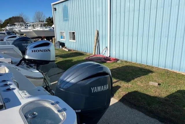 Slide: The Image of 2021 Sailfish 245 DC with Honda and Yamaha outboard motors, parked near a blue building. - 11