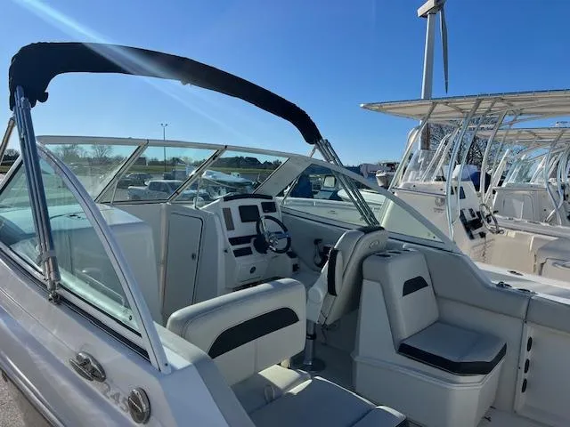 Slide: The Image of 2021 Sailfish 245 DC boat interior with seating and helm, under clear blue sky. - 2