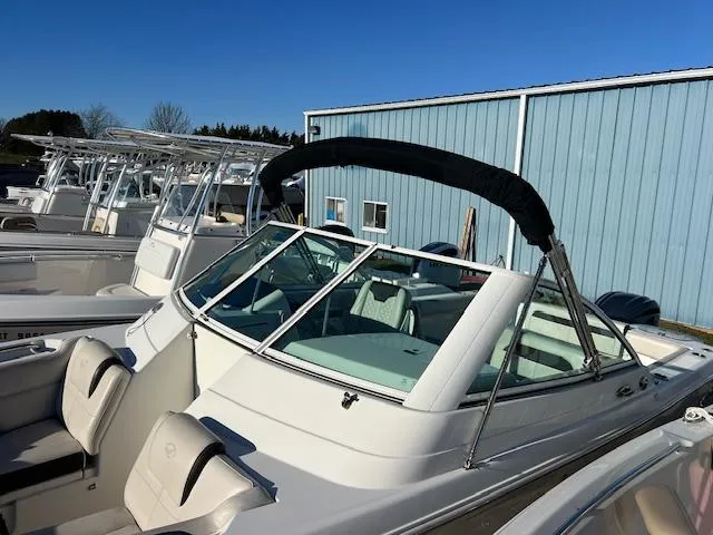 Slide: The Image of 2021 Sailfish 245 DC boat with bimini top, docked near blue building. - 3