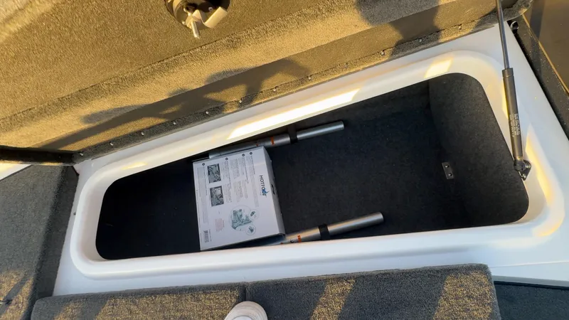 Slide: The Image of 2025 Skeeter ZX150 storage compartment with fishing rods and manual. - 11