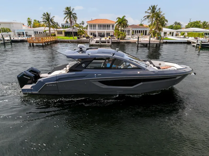 Slide: The Image of 2023 Cruisers Yachts 42 GLS OB on water near waterfront homes and palm trees. - 2