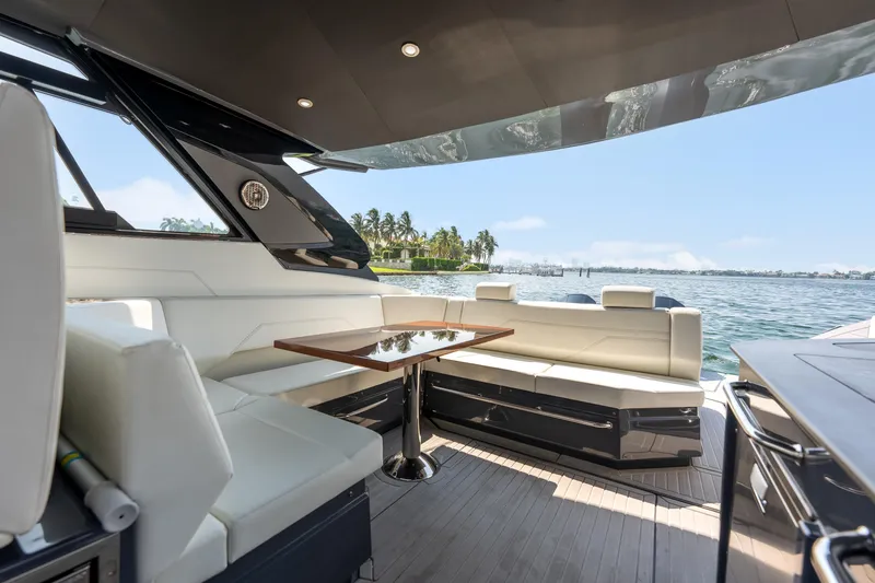 Slide: The Image of 2023 Cruisers Yachts 42 GLS OB interior with seating and table, overlooking water and palm trees. - 36