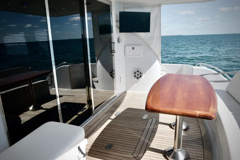 Slide: The Image of 2003 Hatteras 6300 Motor Yacht deck with wooden table, ocean view, and modern amenities. - 22