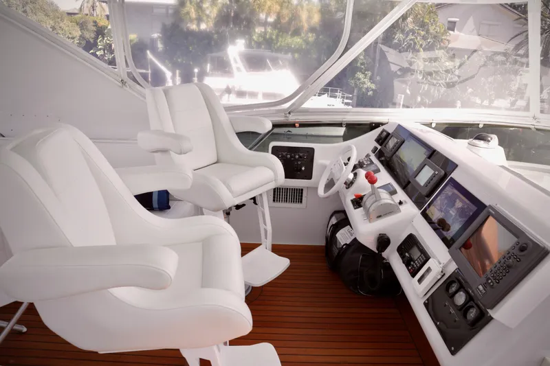 Slide: The Image of Cockpit of 2003 Hatteras 6300 Motor Yacht with white seating and navigation controls. - 25