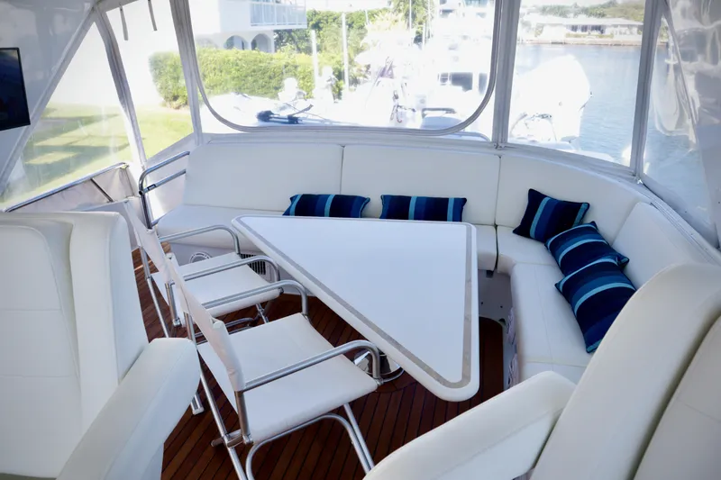 Slide: The Image of 2003 Hatteras 6300 Motor Yacht interior with white seating and triangular table. - 26