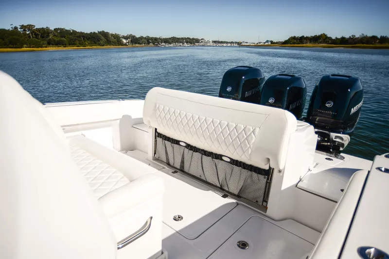 Slide: The Image of 2025 Nor-Tech 340 boat interior with white seating and triple outboard motors on a calm lake. - 37