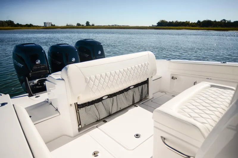 Slide: The Image of 2025 Nor-Tech 340 boat interior with white quilted seating and triple outboard engines. - 38