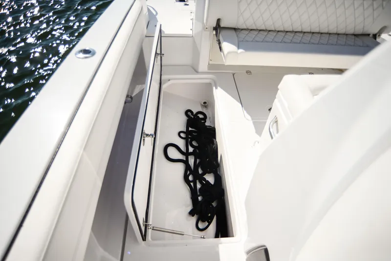Slide: The Image of 2025 Nor-Tech 340 boat storage compartment with ropes, white seating, and water view. - 47