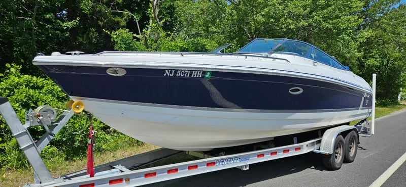 Slide: The Image of 2004 Formula 260 Bowrider boat on trailer, parked on roadside with lush greenery. - 0