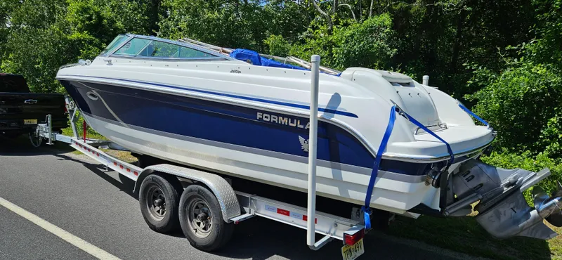 Slide: The Image of 2004 Formula 260 Bowrider boat on trailer, parked on roadside, surrounded by greenery. - 1