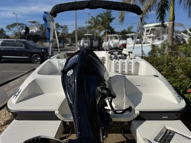 Slide: The Image of 2014 Bayliner 160 Bowrider with outboard motor, parked outdoors under sunny skies. - 10