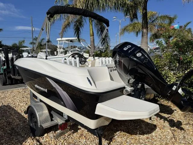 Slide: The Image of 2014 Bayliner 160 Bowrider boat with outboard motor on a trailer, surrounded by palm trees. - 13