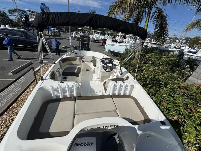 Slide: The Image of 2014 Bayliner 160 Bowrider boat with seating, canopy, and Mercury engine in a marina setting. - 14
