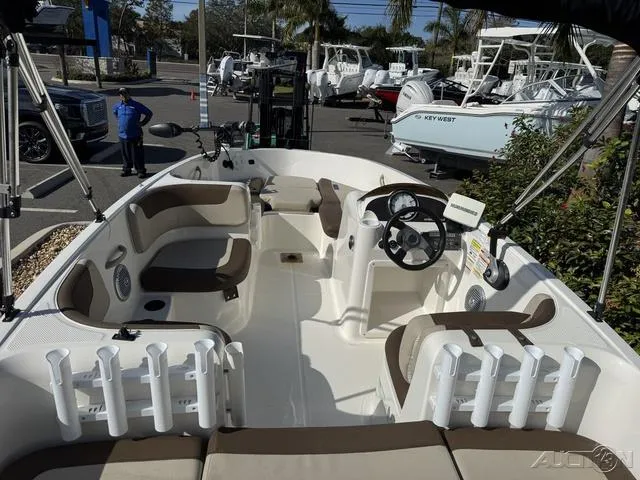 Slide: The Image of 2014 Bayliner 160 Bowrider interior with seating and steering wheel, parked at a marina. - 16