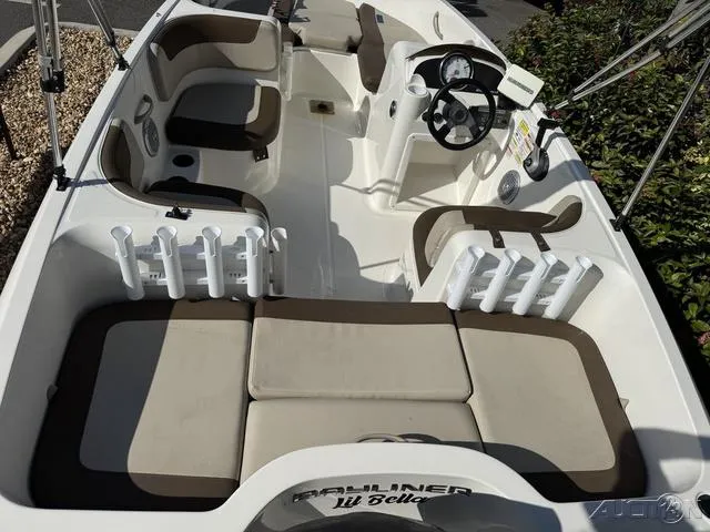 Slide: The Image of 2014 Bayliner 160 Bowrider interior with seating and steering wheel, featuring rod holders. - 17