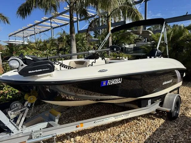 Slide: The Image of 2014 Bayliner 160 Bowrider boat on trailer, surrounded by tropical plants. - 2