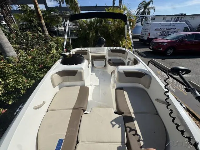 Slide: The Image of 2014 Bayliner 160 Bowrider interior with seating and canopy in a sunny marina setting. - 22
