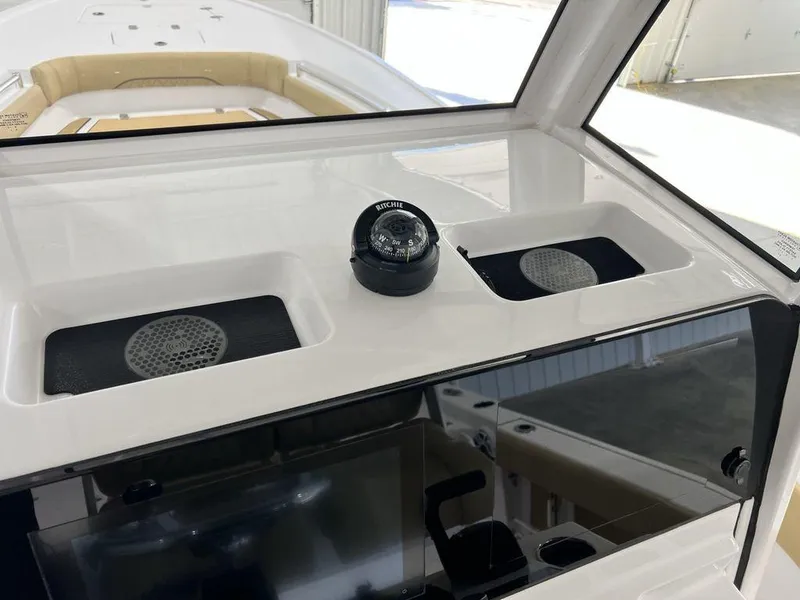 Slide: The Image of 2025 Sportsman Masters 247OE Bay Boat storage compartment with open door and beige seating. - 16
