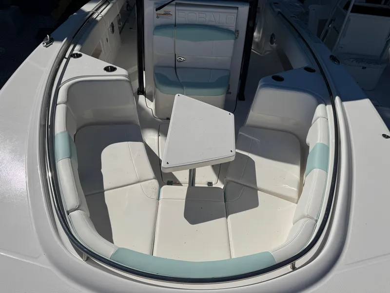 Slide: The Image of 2024 Robalo R302 Center Console boat interior with cushioned seating and table. - 29