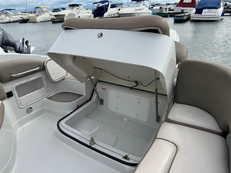 Slide: The Image of 2020 Crownline E235XS boat with open storage compartment, docked at marina. - 10