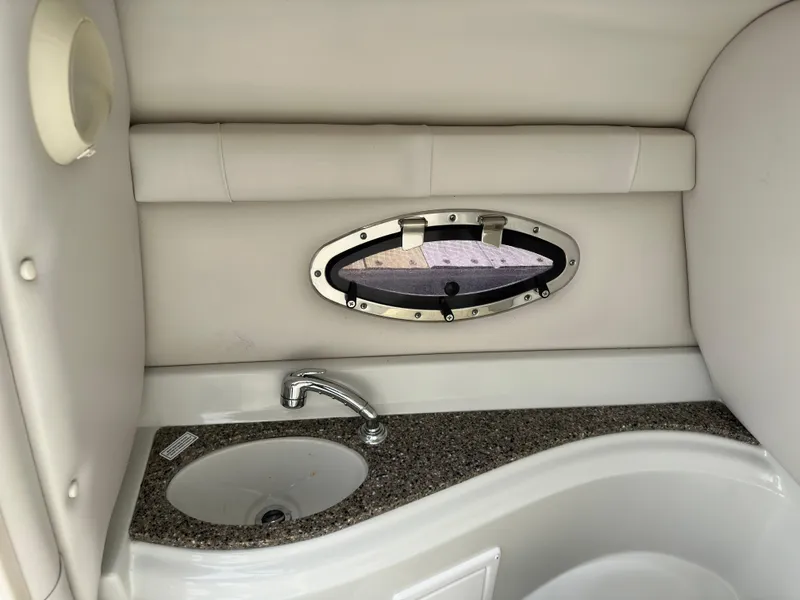 Slide: The Image of 2020 Crownline E235XS boat interior with sink and porthole window. - 18