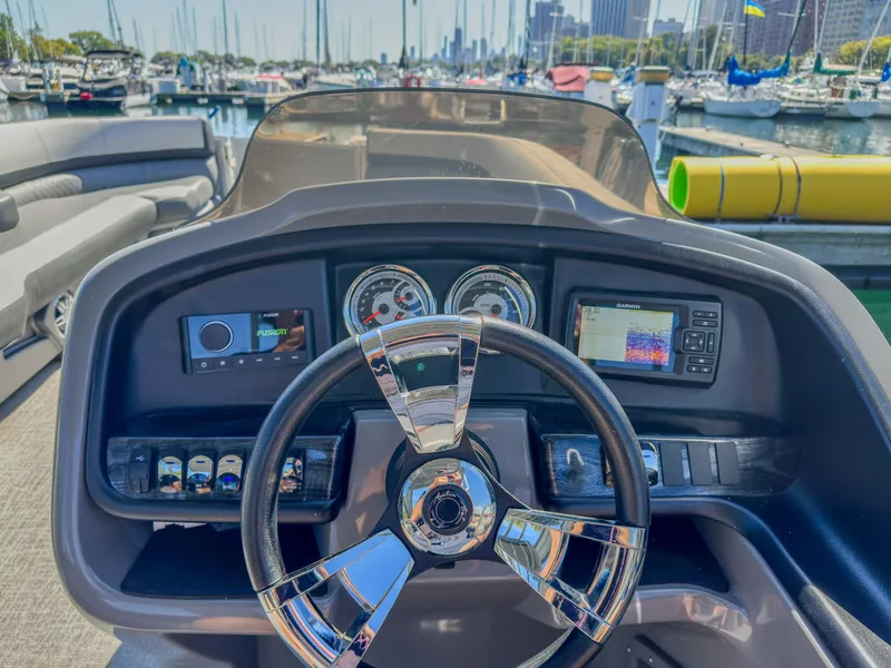 Slide: The Image of 2022 Avalon Catalina FunShip dashboard with steering wheel and controls, docked at marina. - 8